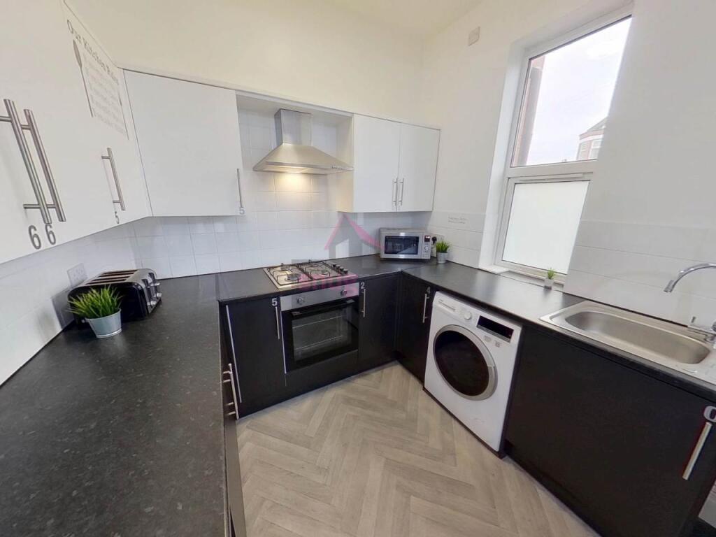 A modern, bright kitchen featuring white cabine...