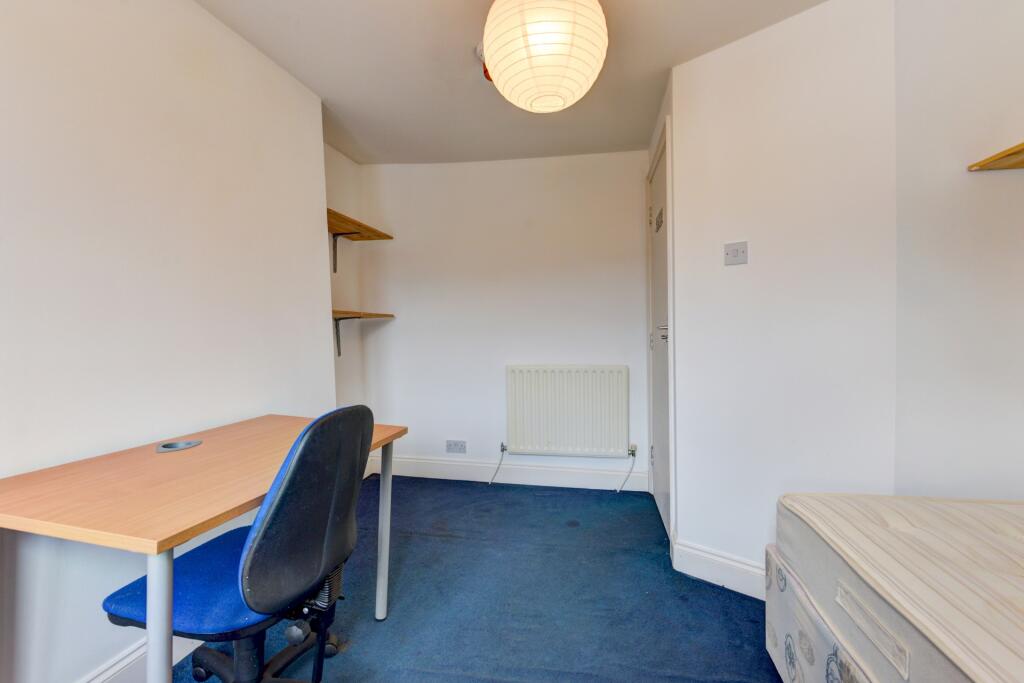 A neat and simple student bedroom featuring a d...