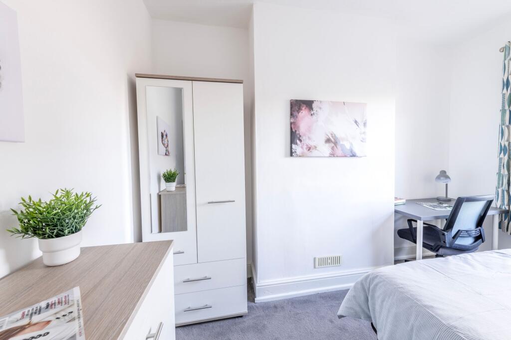 A bright and tidy bedroom with a comfortable be...