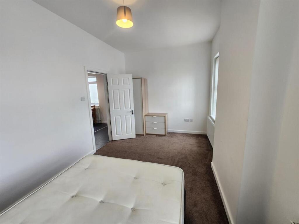 A bright, simple bedroom with a mattress and a ...