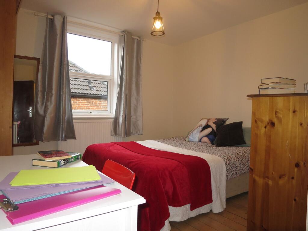 A cozy bedroom featuring a single bed with colo...