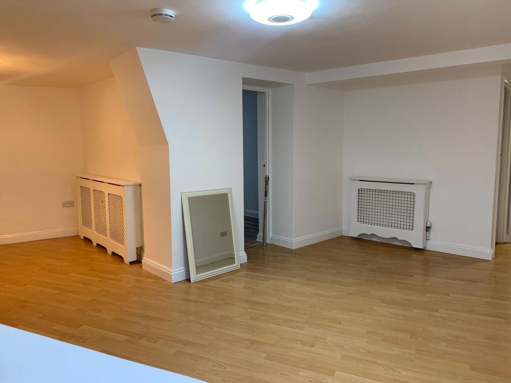 A spacious, clean living room with light wood f...