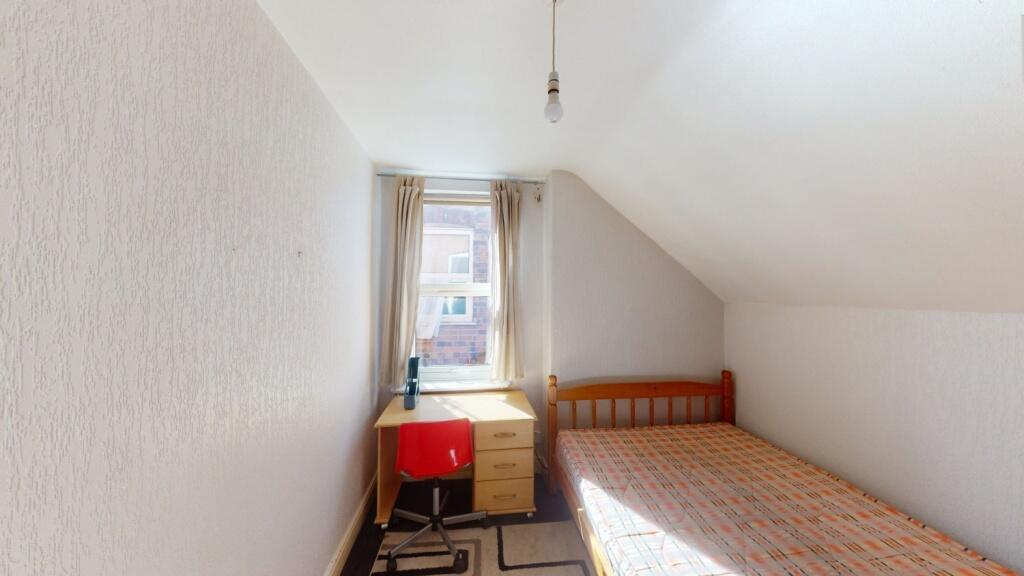 A cozy single bedroom with a wooden bed frame a...