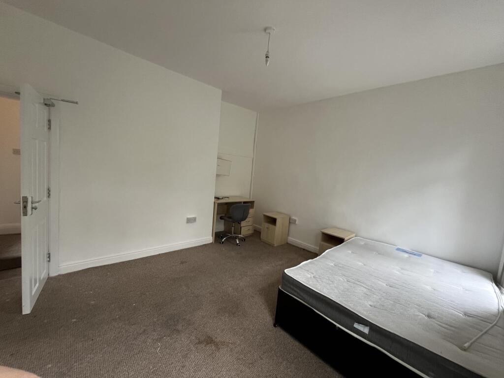 A simple, well-lit single bedroom with a bed an...