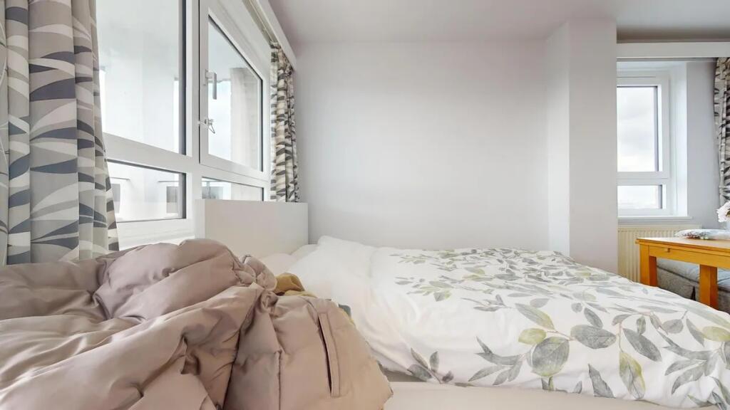 A bright double bedroom with large windows allo...