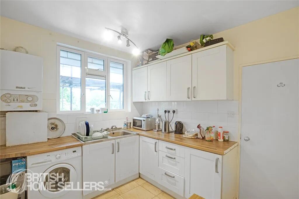 Bright kitchen featuring white cabinetry with w...