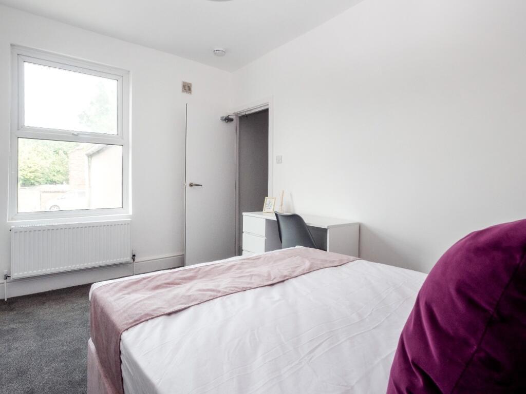 A neat and bright bedroom featuring a comfortab...