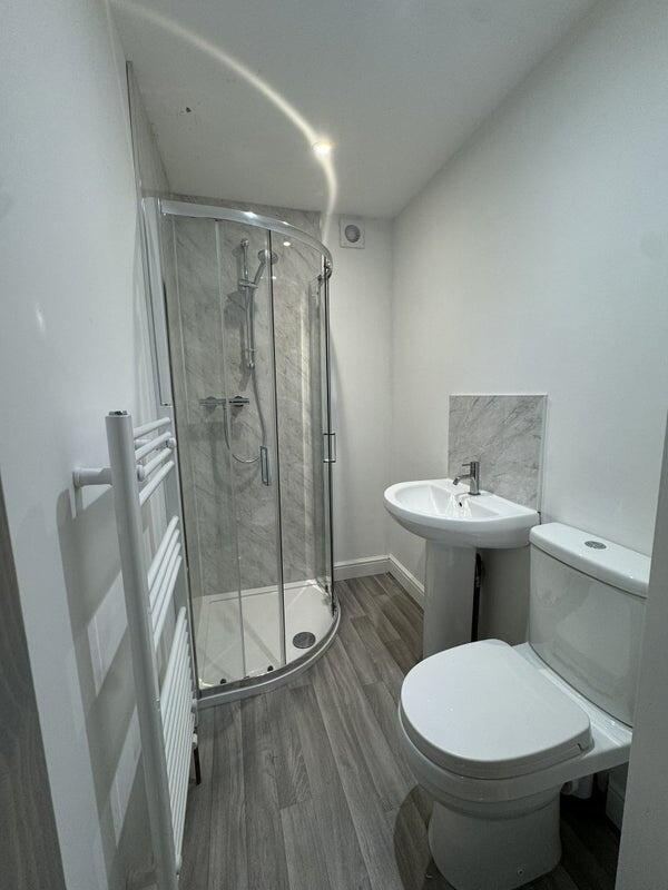 A modern bathroom featuring a curved glass show...