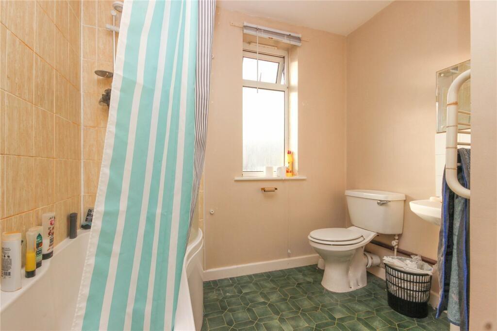 A bright and tidy bathroom featuring a bathtub ...
