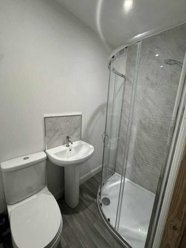 A modern bathroom featuring a curved glass show...