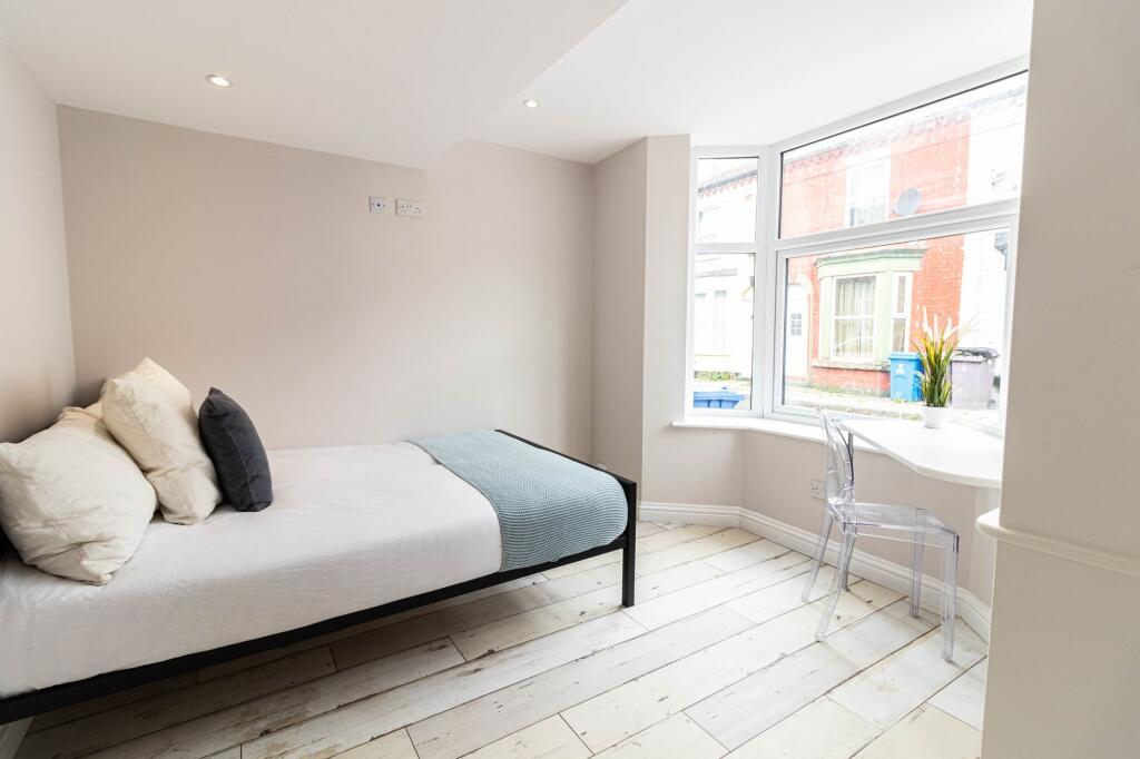 A bright and airy bedroom featuring a simple be...