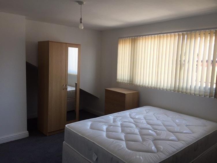 A clean, well-lit bedroom featuring a large win...