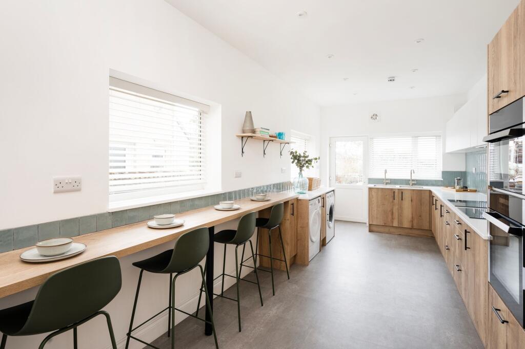 Bright modern galley kitchen with a long wooden...