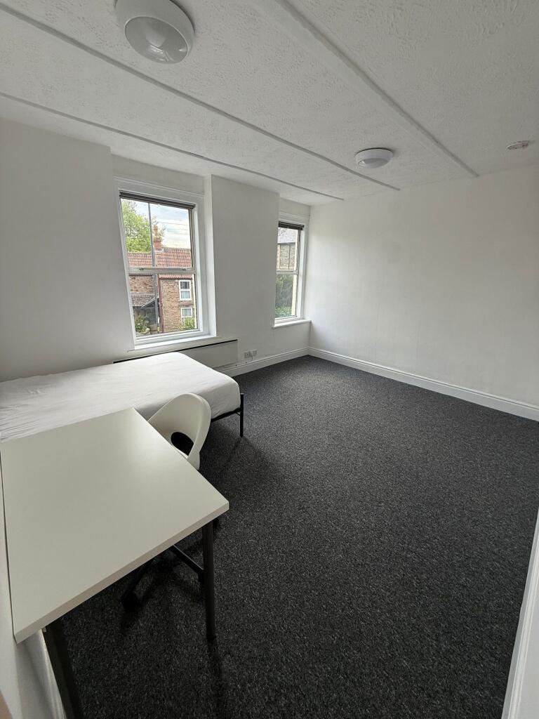 This spacious double bedroom features large win...