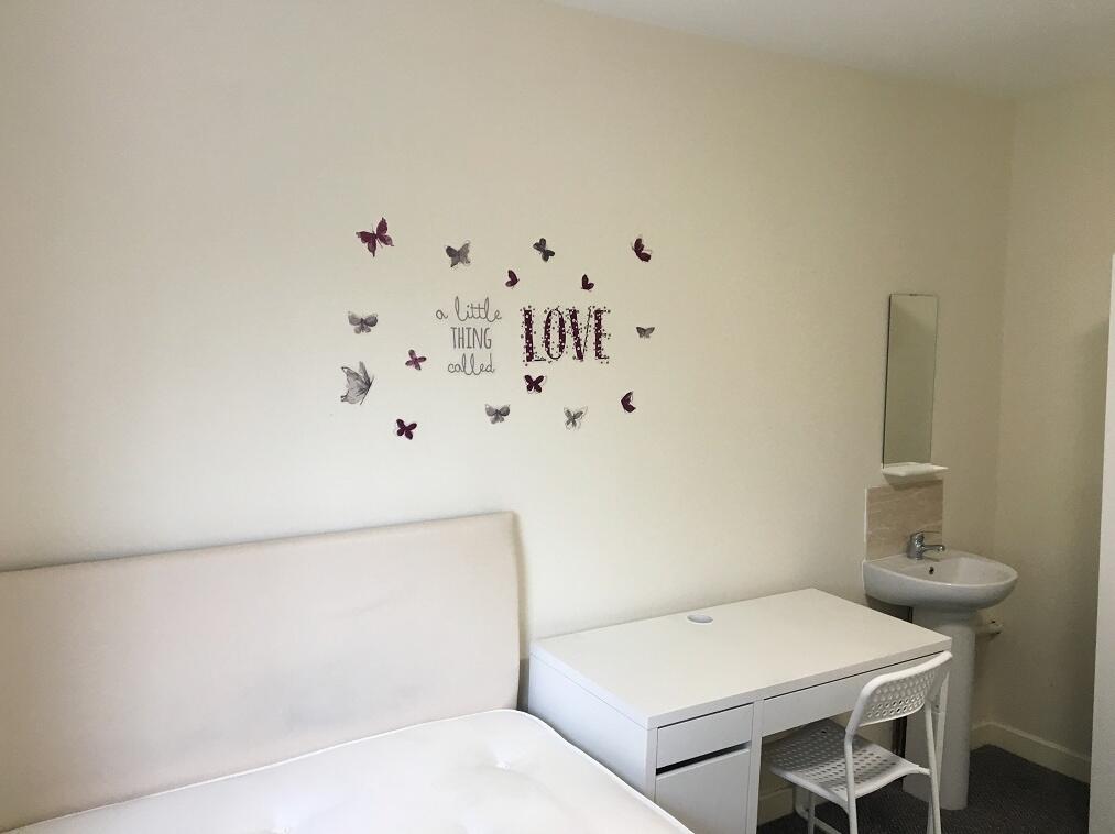A simple, tidy single bedroom featuring a white...