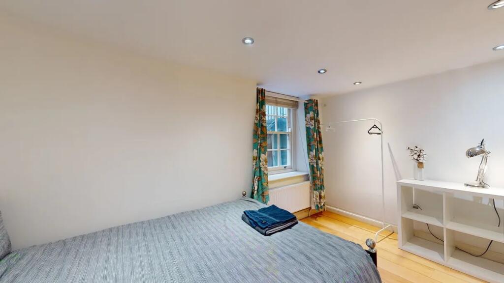 A cozy single bedroom with a neatly made bed, a...