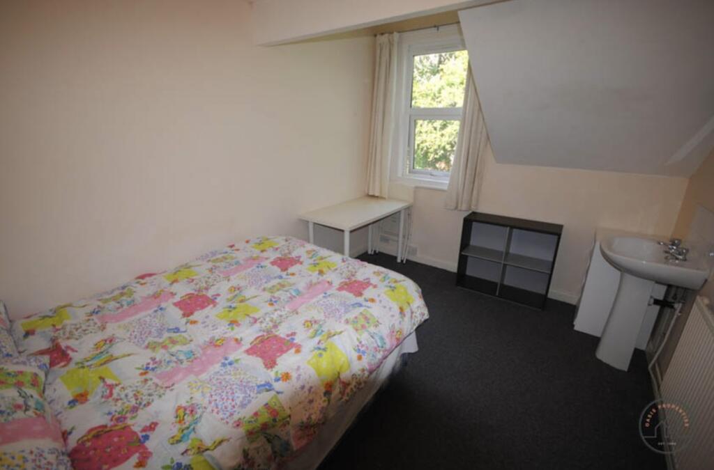 A cozy single bedroom featuring a bed with a co...