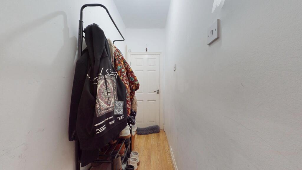 A narrow hallway with wooden flooring and white...