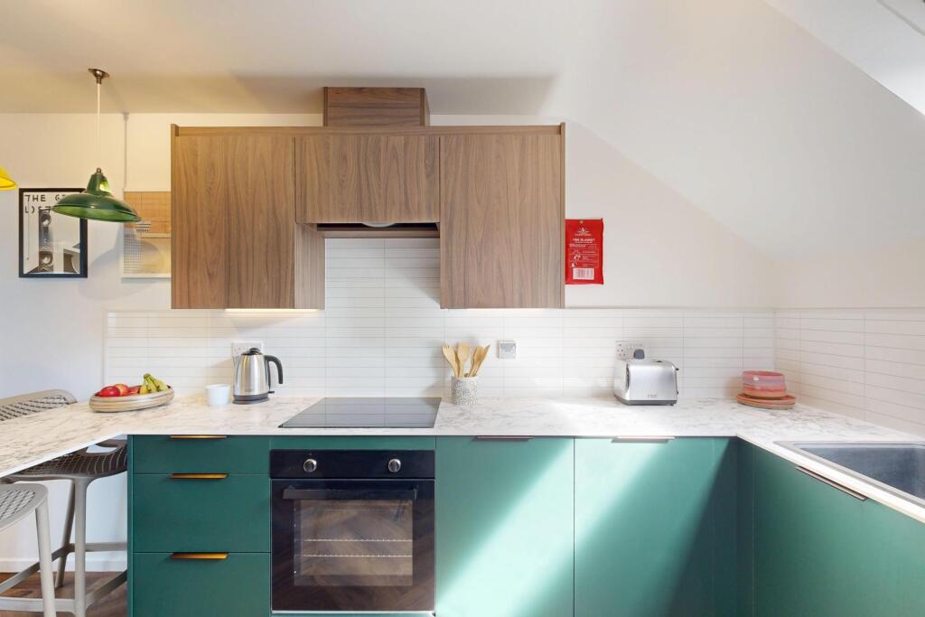 Modern L-shaped kitchen with green lower cabine...