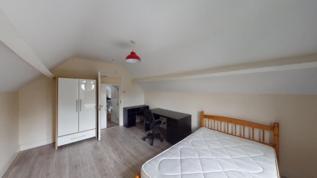 A tidy and simple attic bedroom featuring a sin...