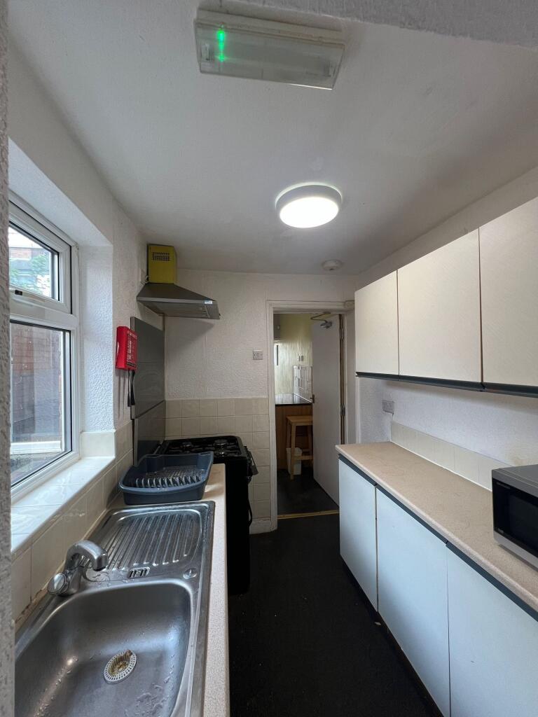 A narrow kitchen featuring a stainless steel si...