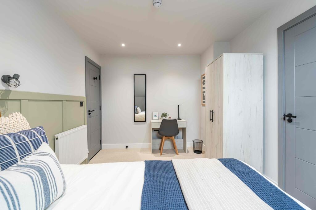 Bright and modern bedroom featuring a neatly ma...