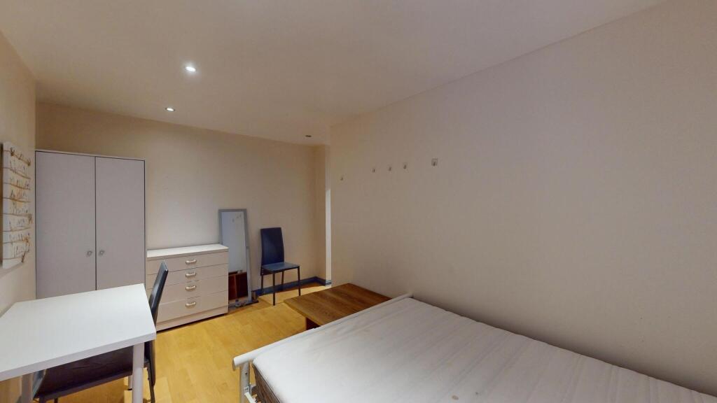 A clean, well-lit bedroom featuring a single be...