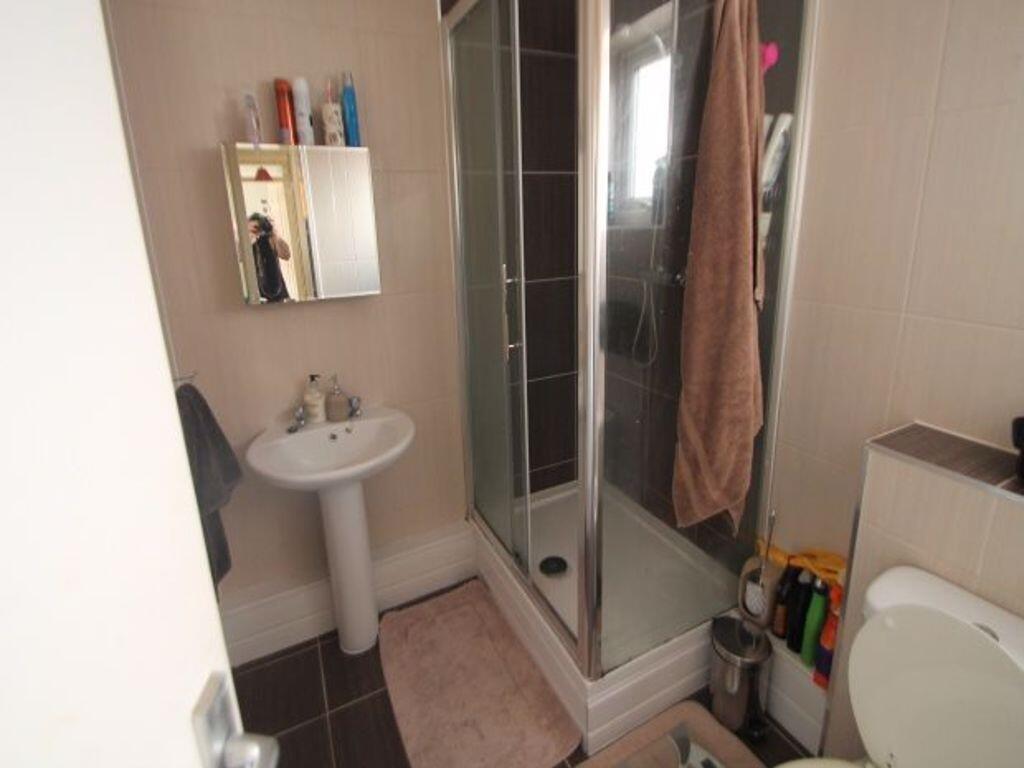 A compact bathroom featuring a corner shower en...