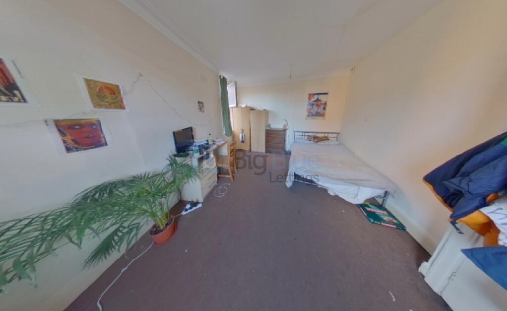 A narrow and tidy room with a single bed, desk,...