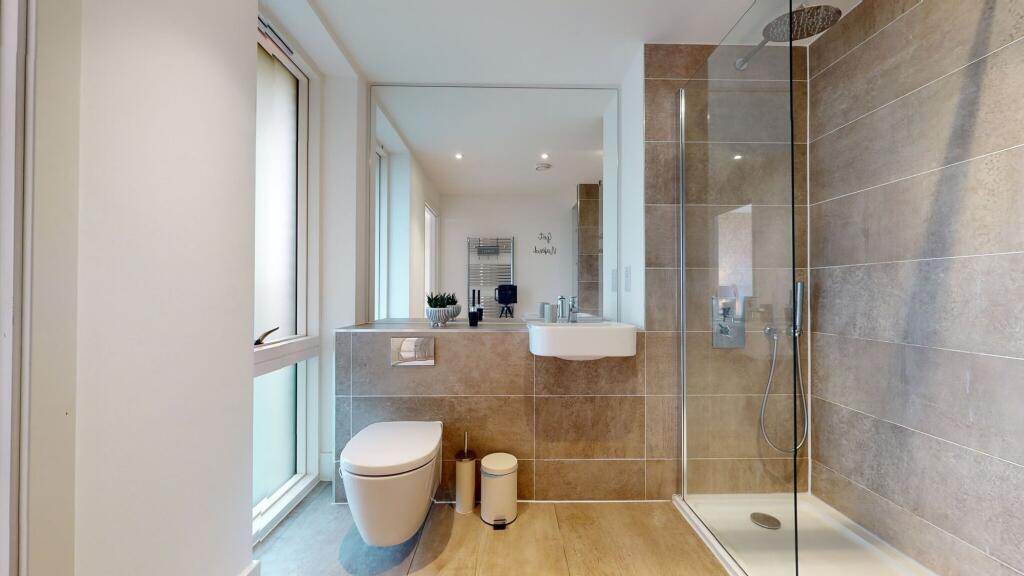 This sleek bathroom features modern beige tiles...