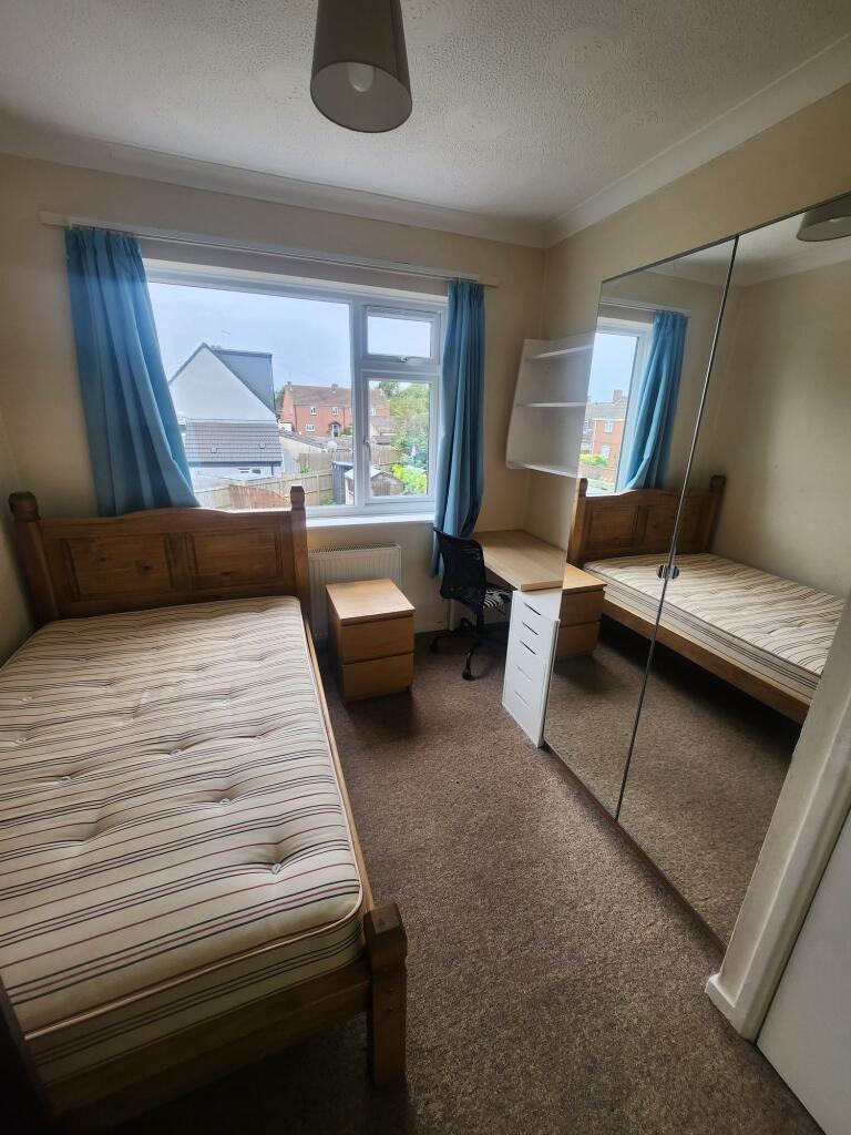 A cozy single bedroom with a wooden bed frame a...