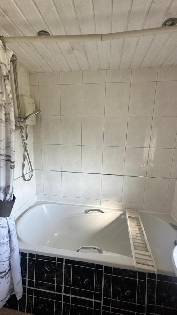 A clean bathroom featuring a bathtub with a sho...