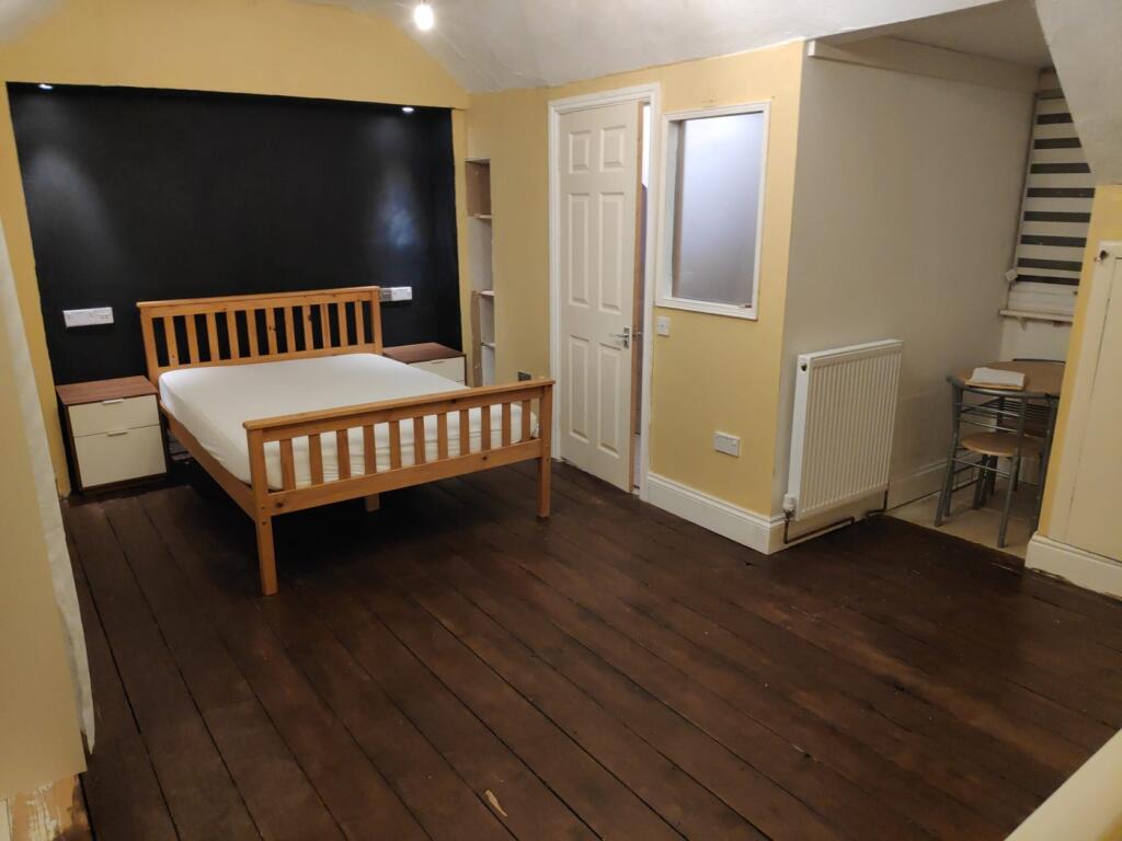 A spacious double bedroom featuring a wooden be...