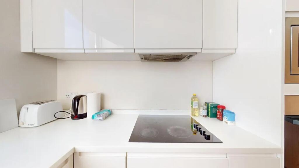 A modern, clean kitchen with sleek white cabine...