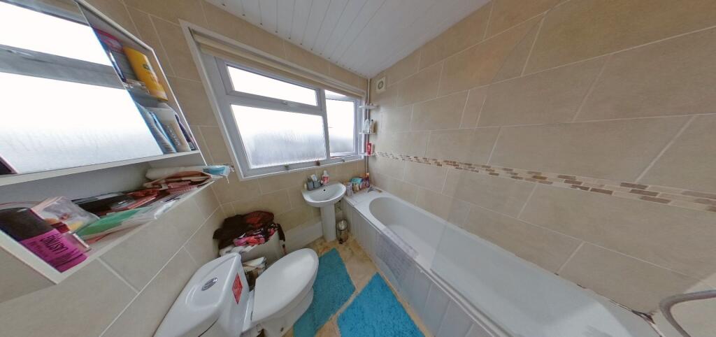 Bright, tiled bathroom with a bath, pedestal si...