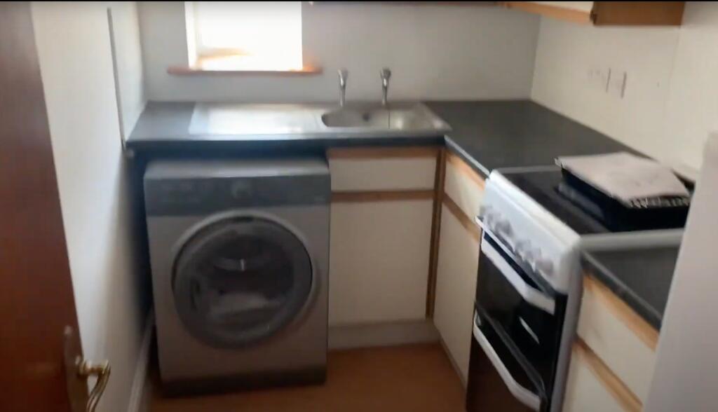 A compact kitchen with essential appliances, in...