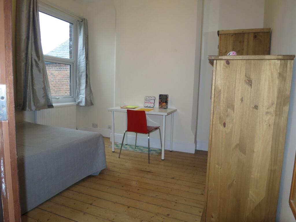 A cozy bedroom featuring a simple bed next to a...