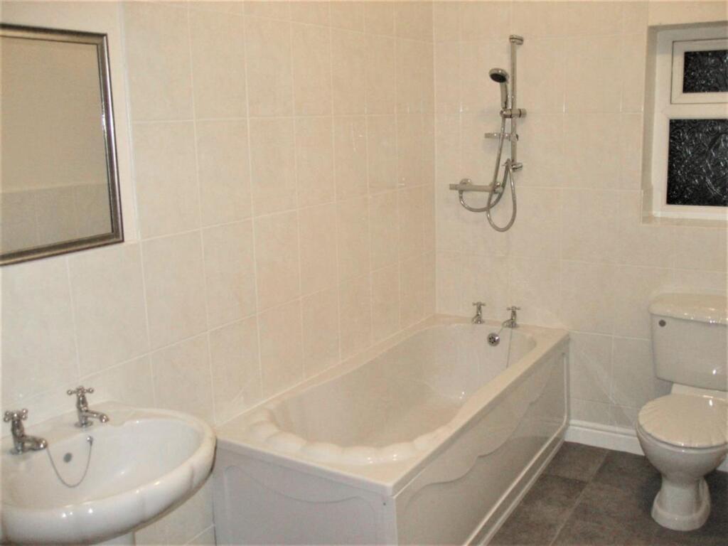 A bright and clean bathroom suite featuring a f...