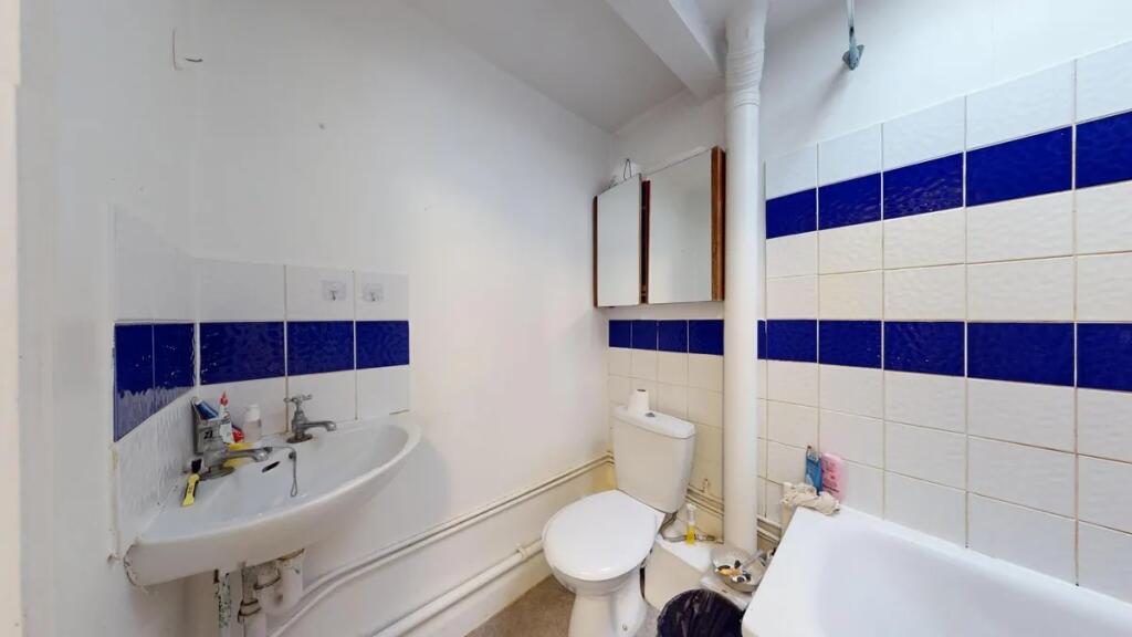 A compact bathroom featuring a white sink, toil...