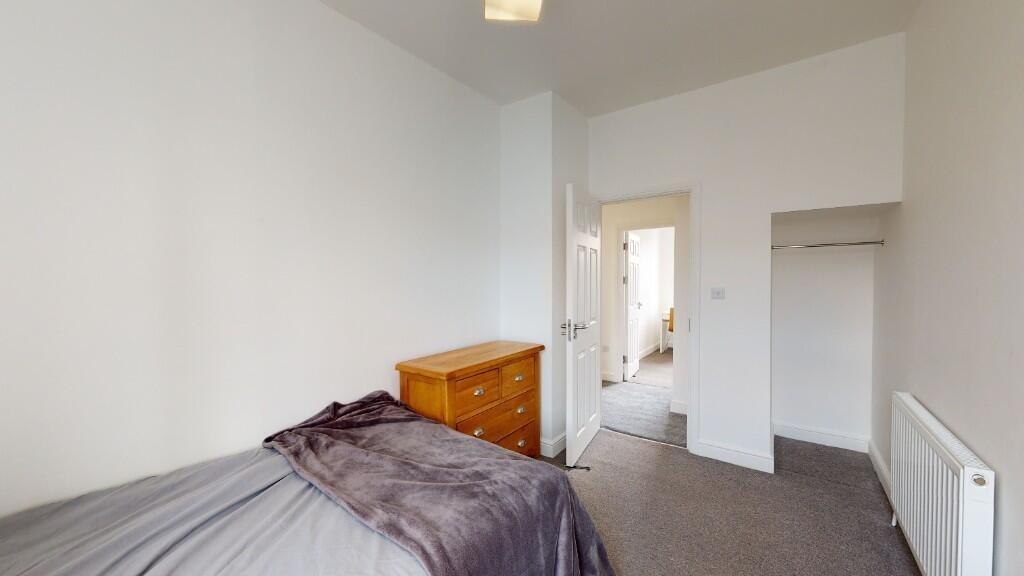 A neat and tidy single bedroom featuring a bed ...