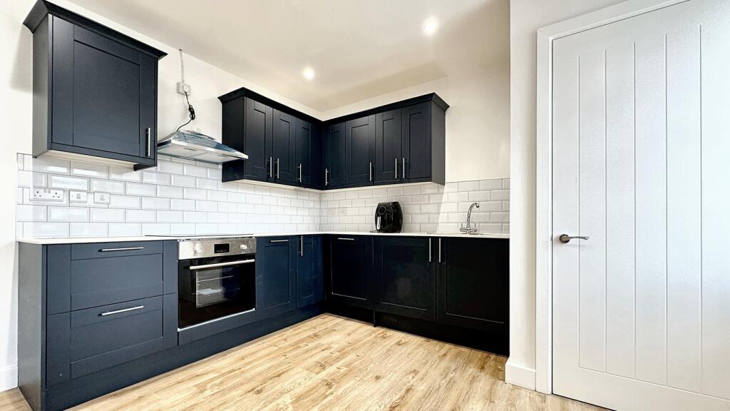 A modern kitchen featuring sleek dark cabinetry...
