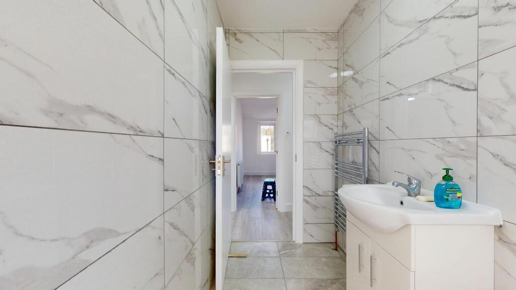 Modern bathroom featuring white marble-effect t...