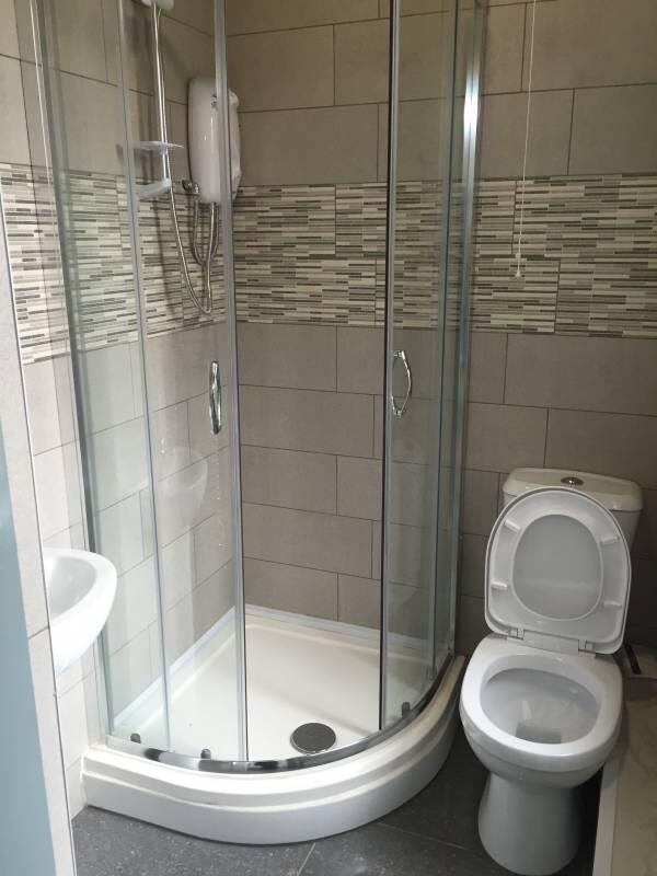 Modern tiled bathroom with a curved glass showe...