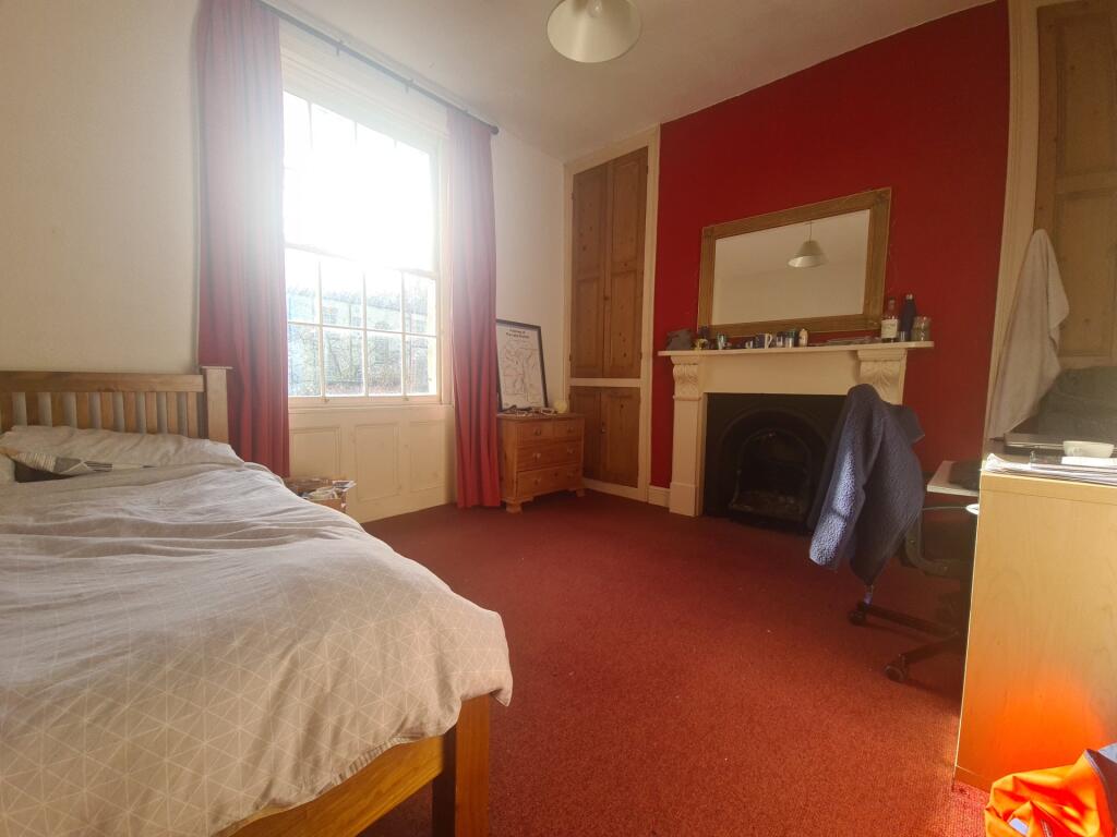 A cozy bedroom featuring a double bed, a window...