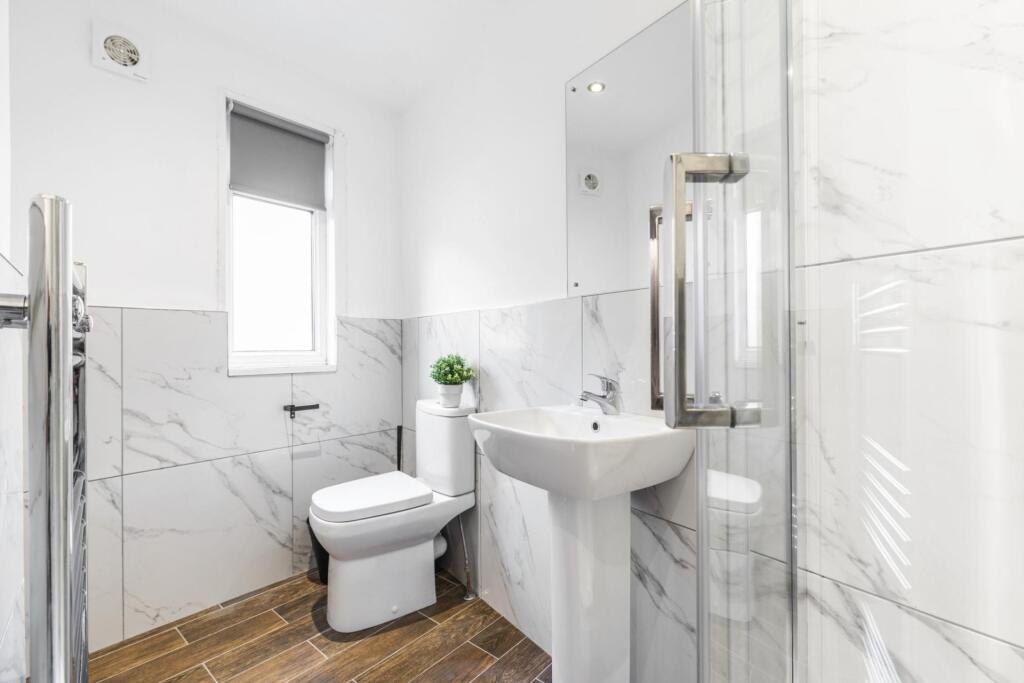 Bright, modern bathroom with marble-effect tili...