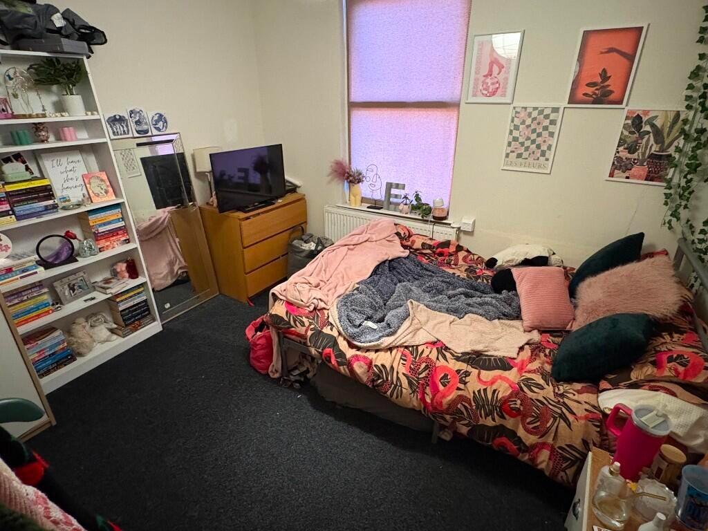 Cozy single bedroom with a colorful floral beds...