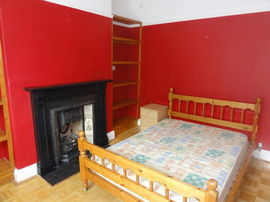 A cozy double bedroom featuring warm red walls,...