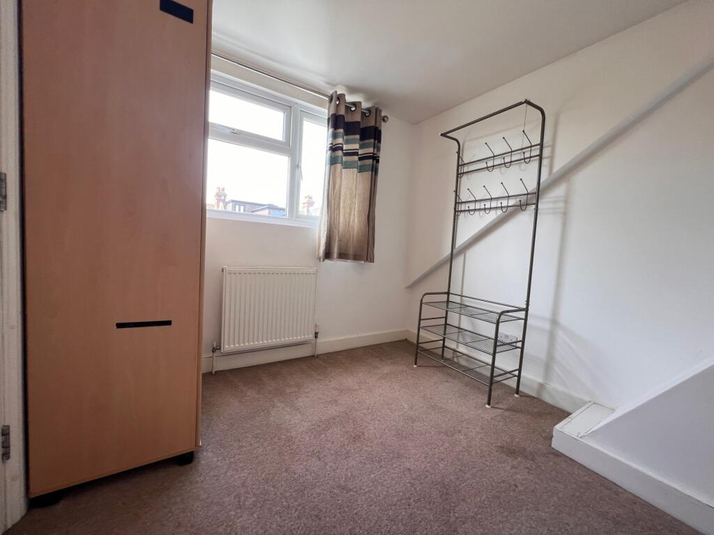 A simple bedroom with a window allowing natural...