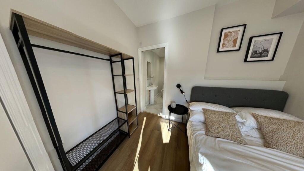 A well-lit bedroom featuring a neatly made bed ...