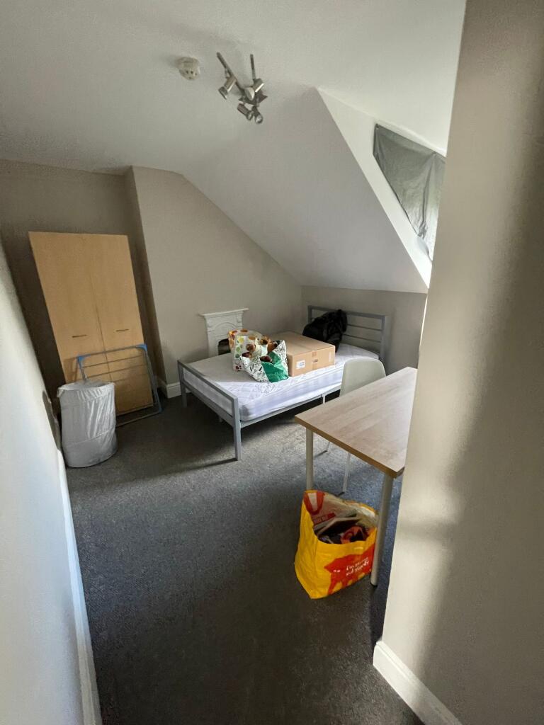 A modest bedroom with a single bed, a small war...